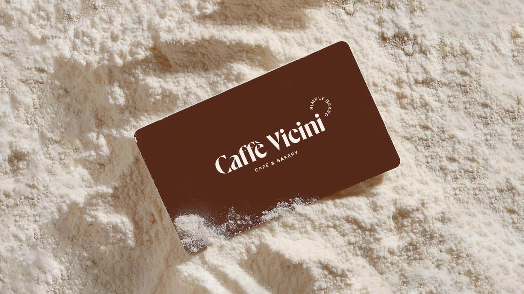 Caffe Vicini Café & Bakery gift card resting on a bed of flour, showcasing the Simply Baked brand identity
