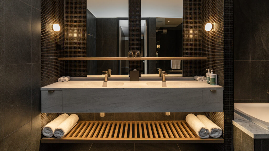 Double-sink vanity in the Presidential Suite at Novotel Sydney Cabramatta, with dark tiles, mirrors, and folded towels.