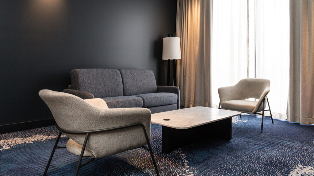 Presidential Suite lounge with a grey sofa, armchairs and marble coffee table at Novotel Sydney Cabramatta