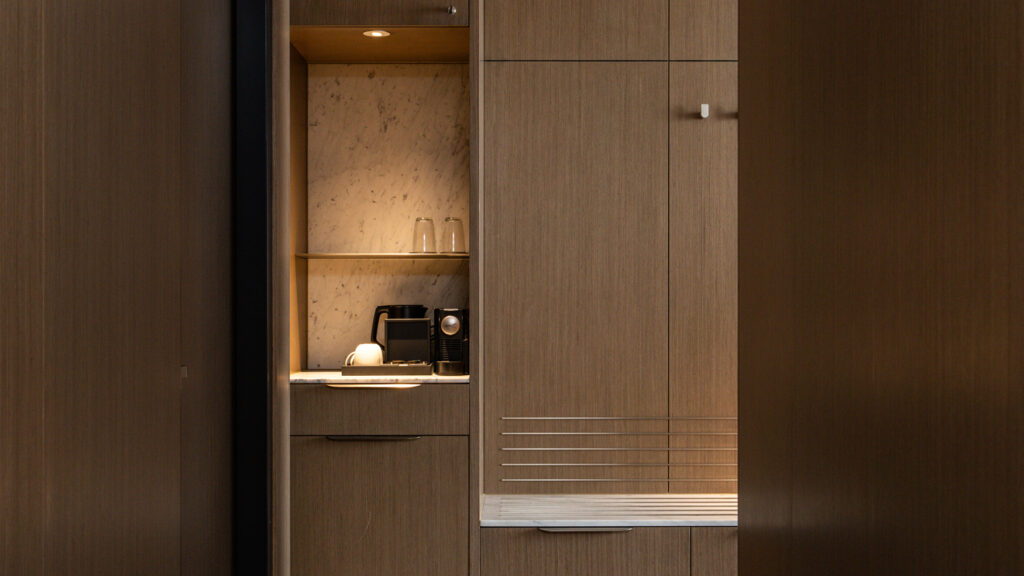 Built-in minibar with a coffee machine beside timber wardrobes in the Presidential Suite at Novotel Sydney Cabramatta