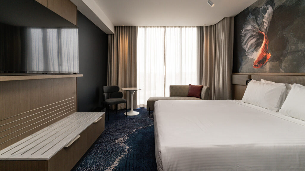 Spacious king bedroom in the Presidential Suite at Novotel Sydney Cabramatta with TV, lounge seating, and large windows.