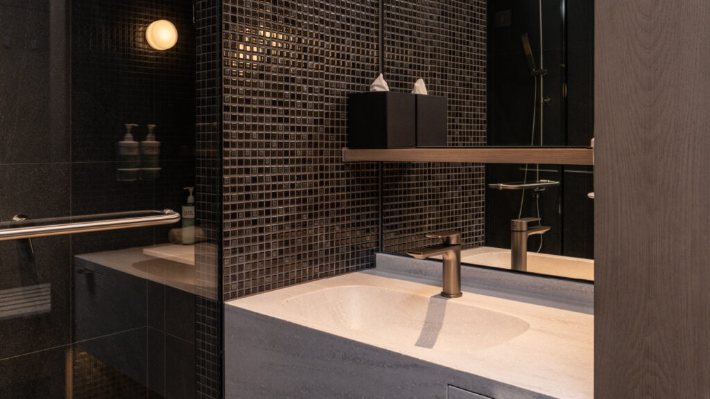 Bathroom in the Deluxe Twin room at Novotel Sydney Cabramatta with sleek black tiles, walk-in shower, and vanity.