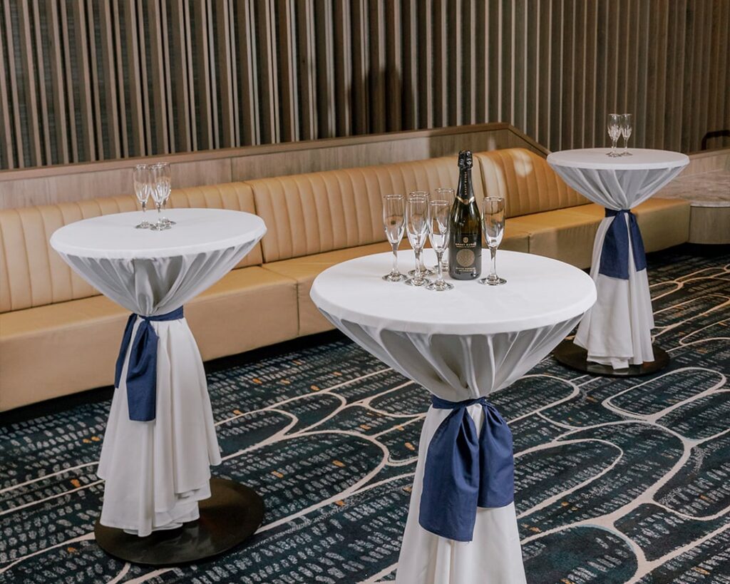 End of year function setup with white linen cocktail tables, blue sashes and champagne at Cabravale Club Resort