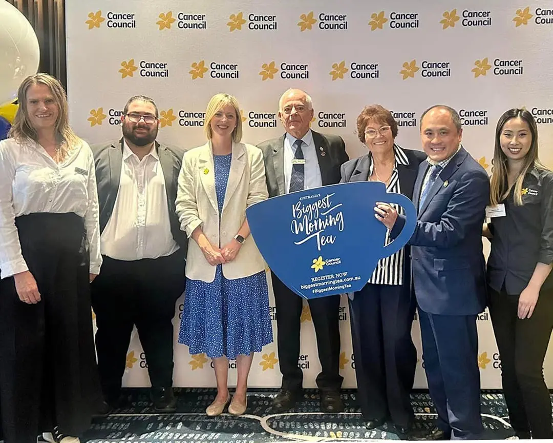 Community representatives pose with “Australia’s Biggest Morning Tea” sign at a Cancer Council NSW fundraising event that was held in The Space Event Centre