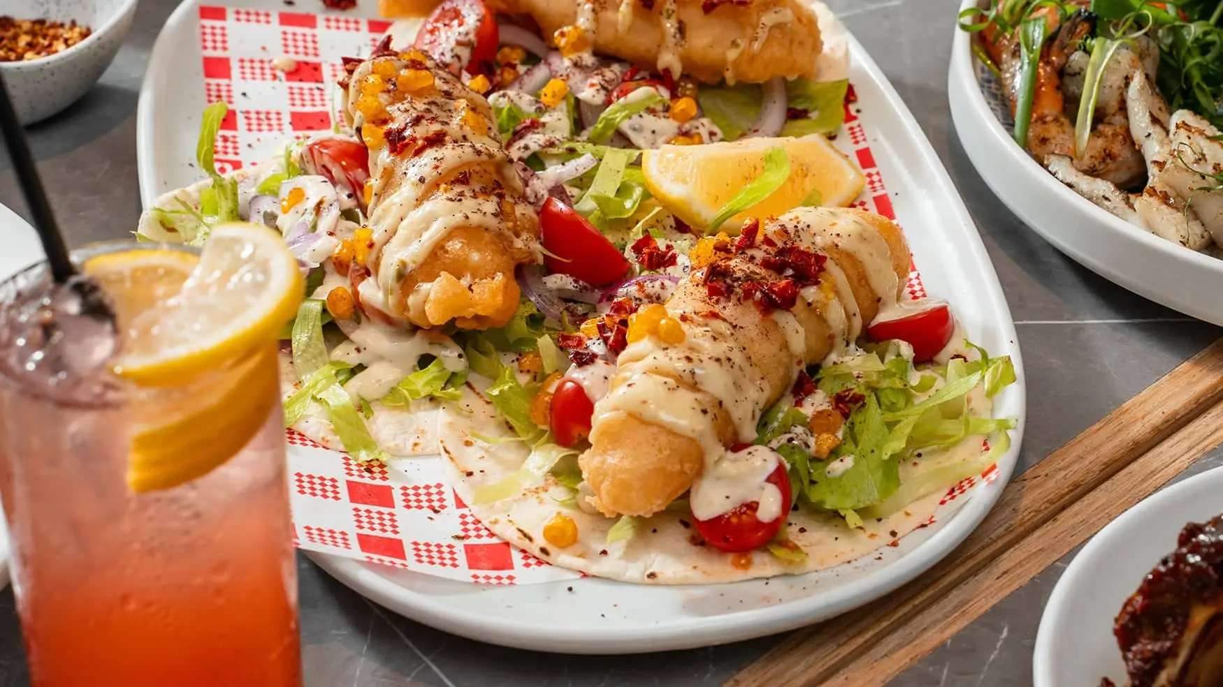 Fish taco with battered fish, tortilla bread, corn kernels, lettuce, tomato, onion and tartare sauce at Bistro 1925