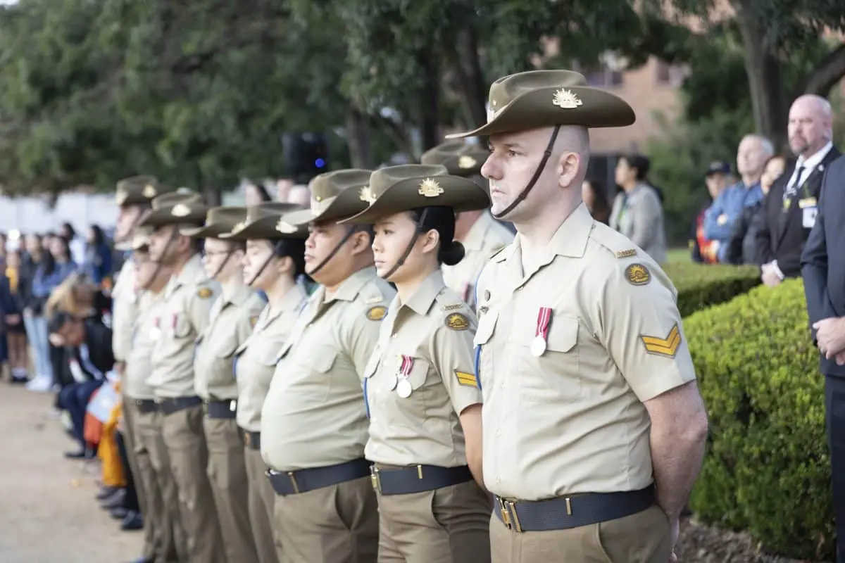 Uniformed Australian service members stand in formation during an ANZAC Day remembrance ceremony