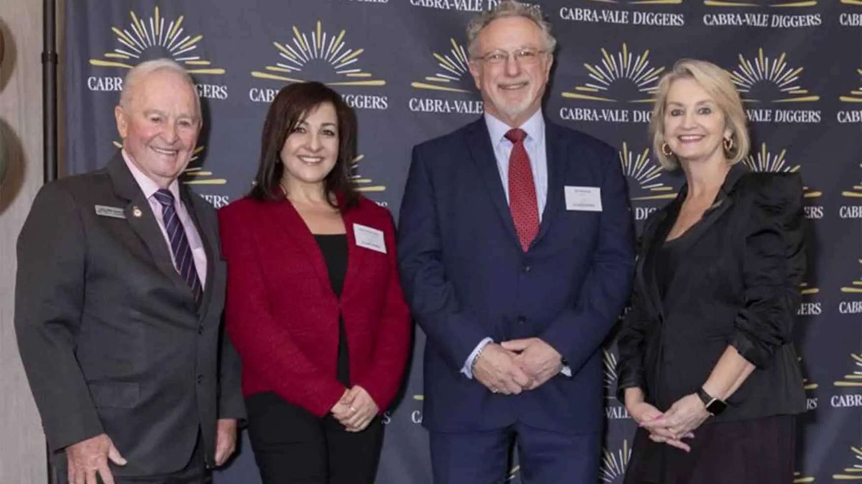 Four guests posing for a photo at the Cabravale Club Resort ClubGRANTS Presentation, standing in front of a Cabravale Diggers branded backdrop at Cabravale.