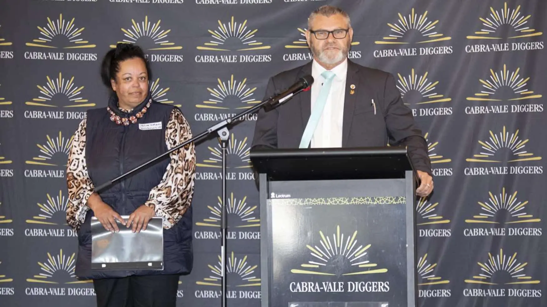 Speaker presenting at a podium during the Cabravale Club Resort ClubGRANTS event at Cabravale, with another attendee standing beside him