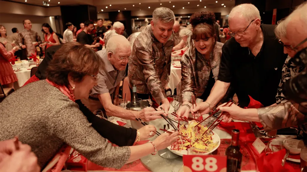 Board directors tossing lo hei prosperity salad together at a Lunar New Year celebration at Cabravale