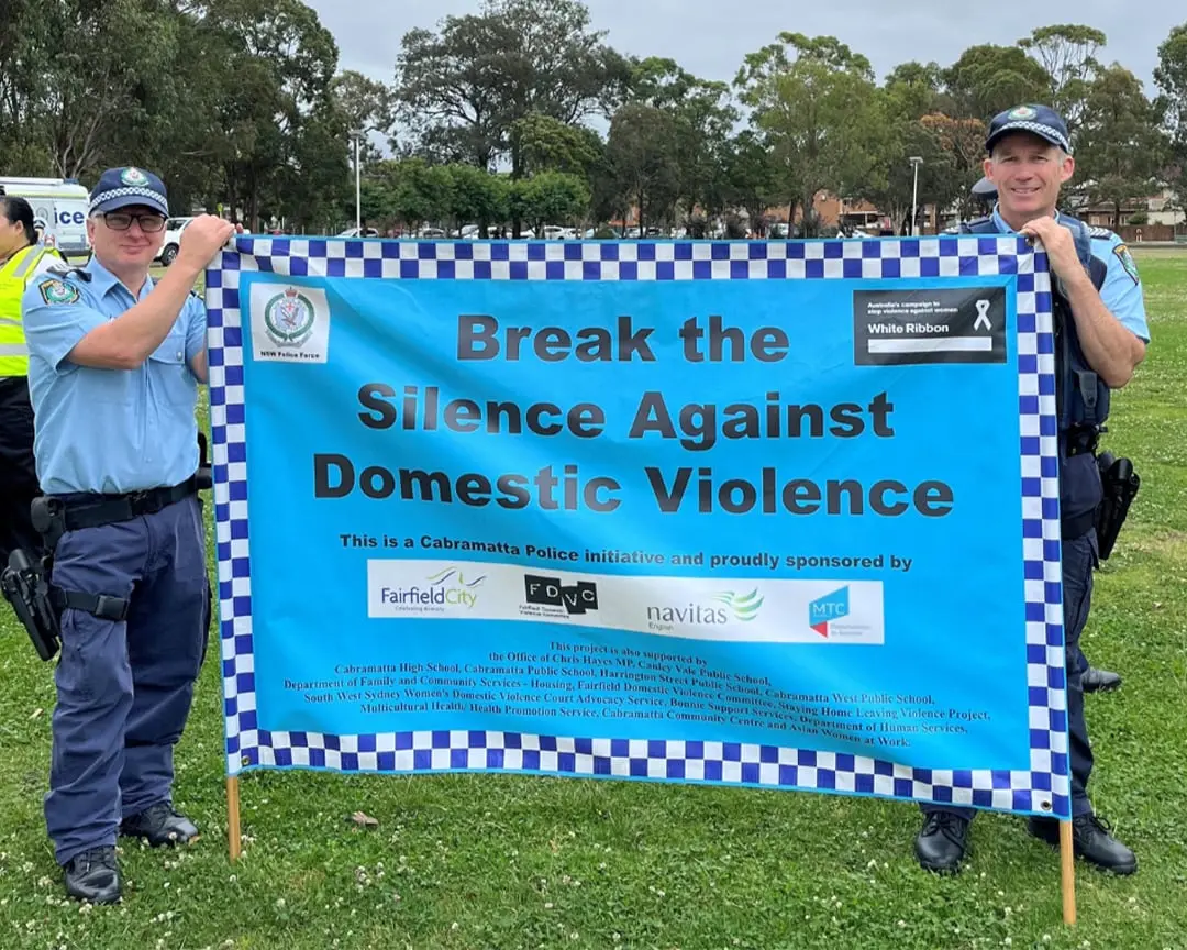 Two NSW Police officers hold a blue banner reading “Break the Silence Against Domestic Violence” during the Cabramatta Domestic Violence Walk at Cabravale Memorial Park.