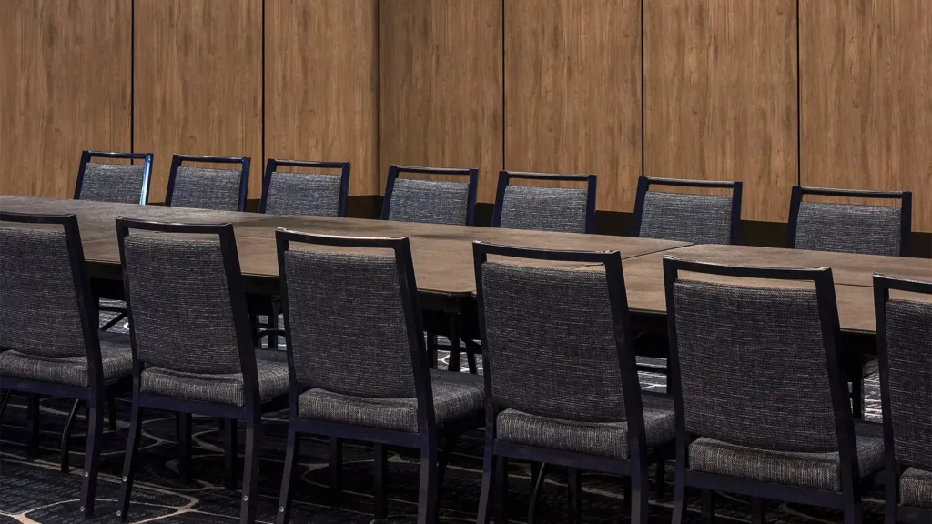 Modern meeting room with long conference tables and upholstered chairs set against warm timber walls for corporate events