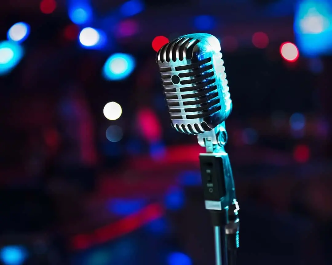 Vintage silver stage microphone in close up with red and blue bokeh stage lights in the background
