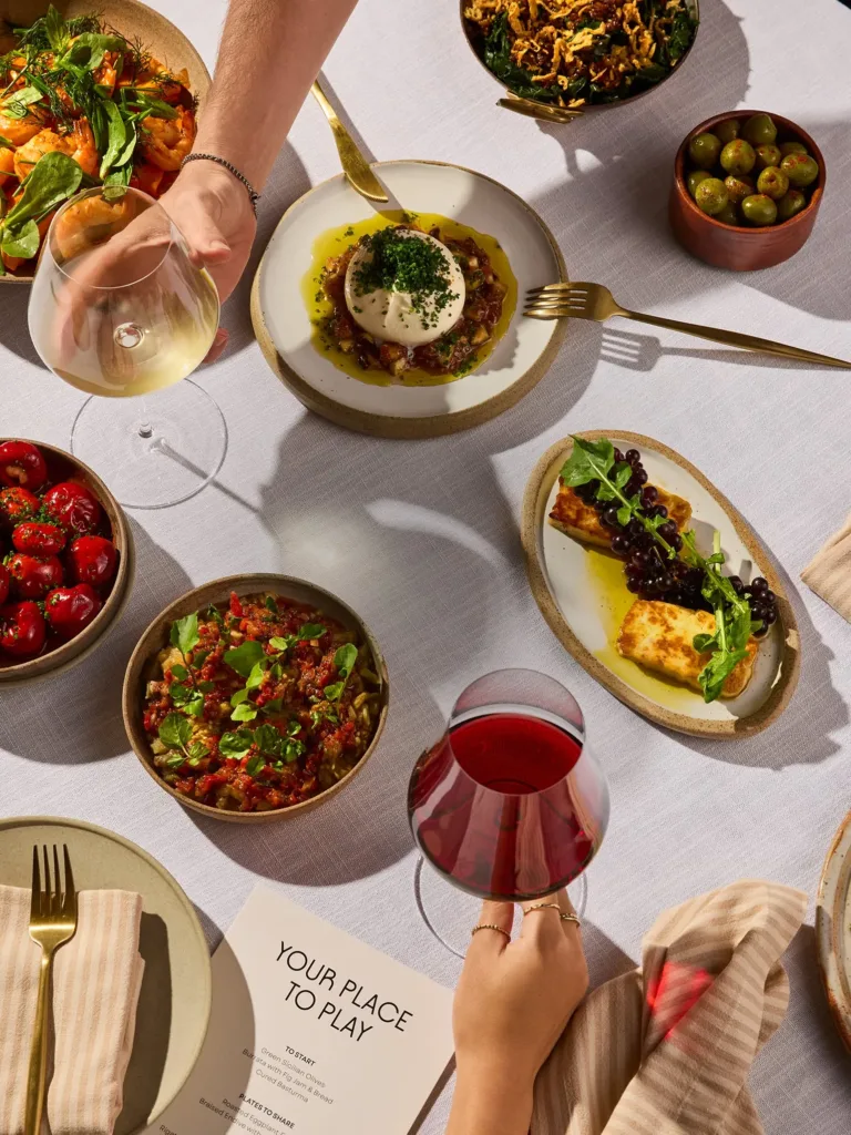 Shared plates, salads and red wine on a table, part of the premium dining in Canley Vale at Cabravale Club Resort
