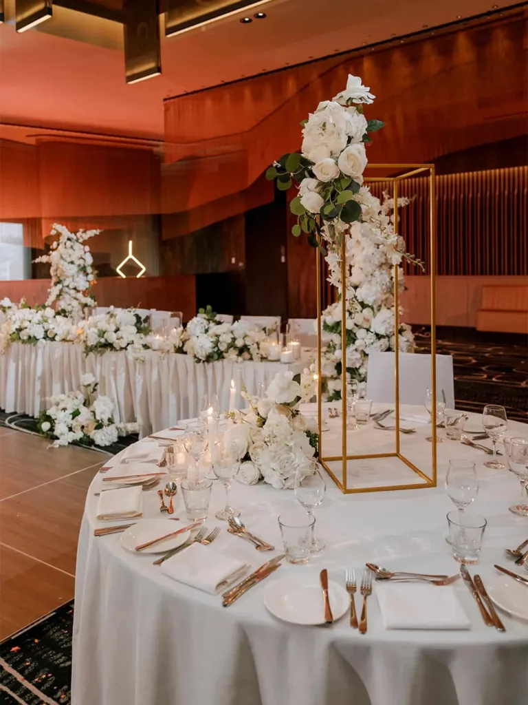 Reception tables with white linen and tall white floral centrepieces, set up for functions at Cabravale Club Resort