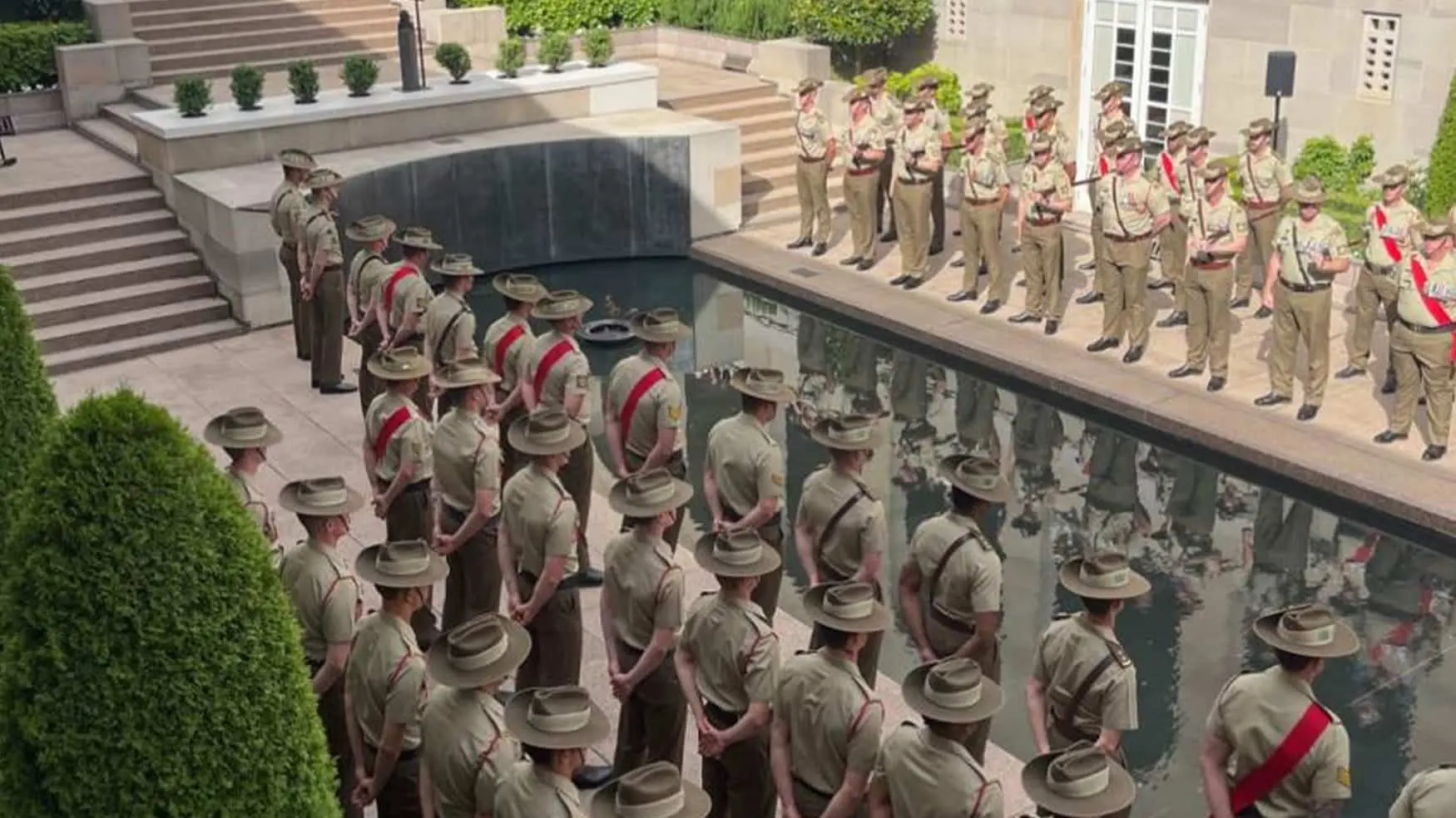 Australian Army personnel stand in formation beside the Reflecting Pool during the Last Post Ceremony at the Australian War Memorial.