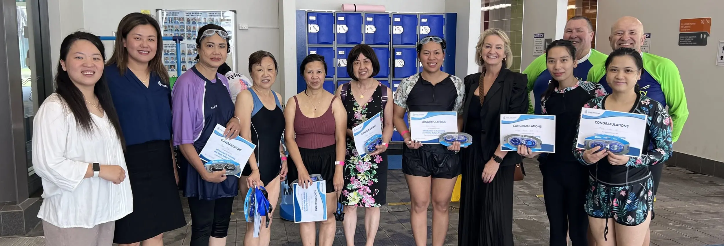Participants and organisers pose at a leisure centre, holding certificates from the Learn to Swim program for CALD communities at Cabravale Club Resort.