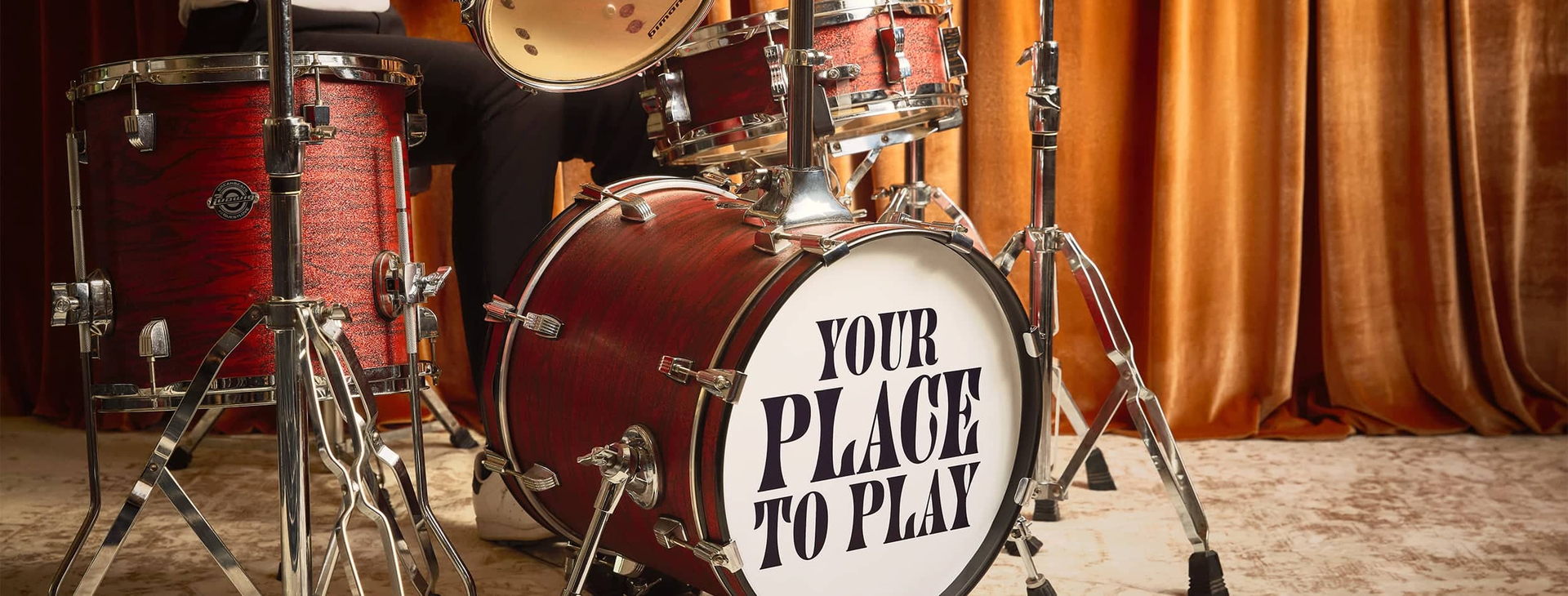Live entertainment at Cabravale Club Resort — drum kit on stage with ‘Your Place To Play’ bass drum in front of gold curtains.