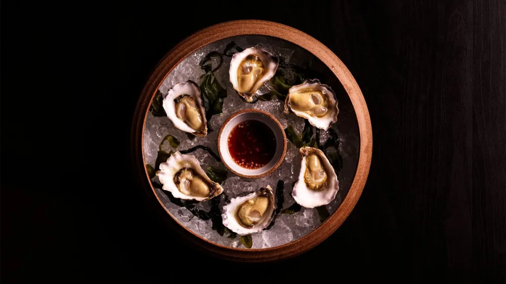 Oyster platter served on ice with dipping sauce in a refined Magma by Dany Karam presentation