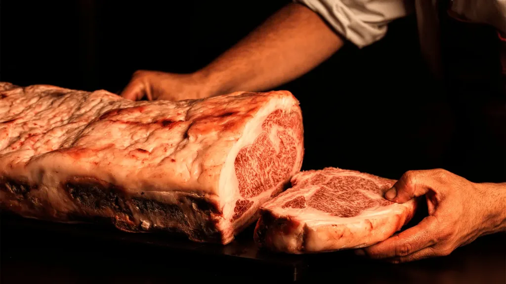 A large marbled beef cut with a thick slice held by hand