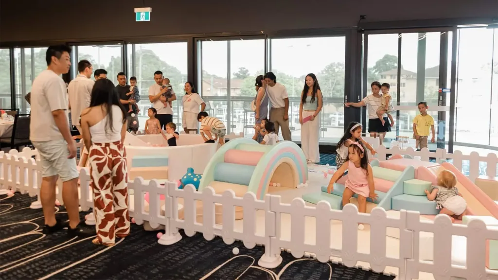 Adults and children around a pastel soft play area set up inside a function room for a private birthday party