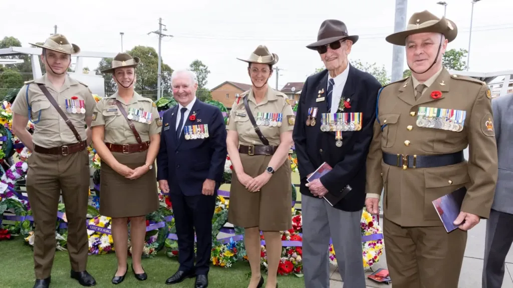 Veterans and Army personnel wearing medals in front of wreaths at the Remembrance Day 2024 service at Cabravale
