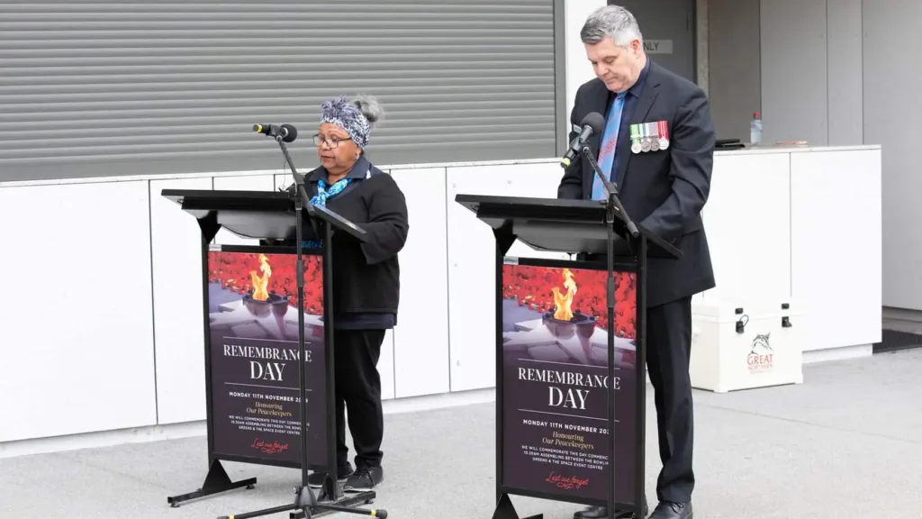 Two speakers stand at lecterns marked “REMEMBRANCE DAY,” delivering readings during Cabravale Club Resort service.