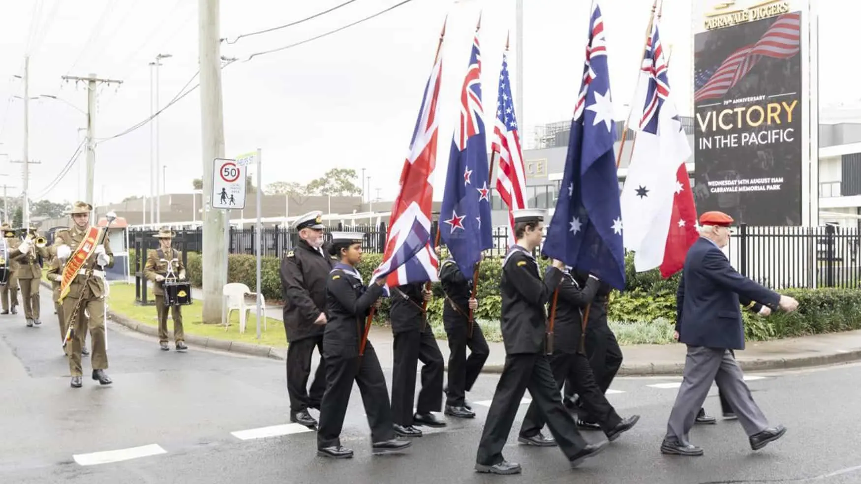Marching procession carrying Australian, Allied and service flags during the Victory in the Pacific 2024 commemorative parade at Cabravale Memorial Park.