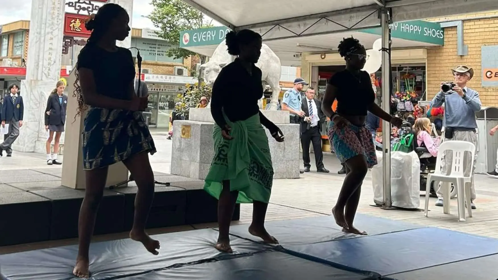 Traditional dancers perform barefoot in coordinated steps as onlookers watch at a community event.