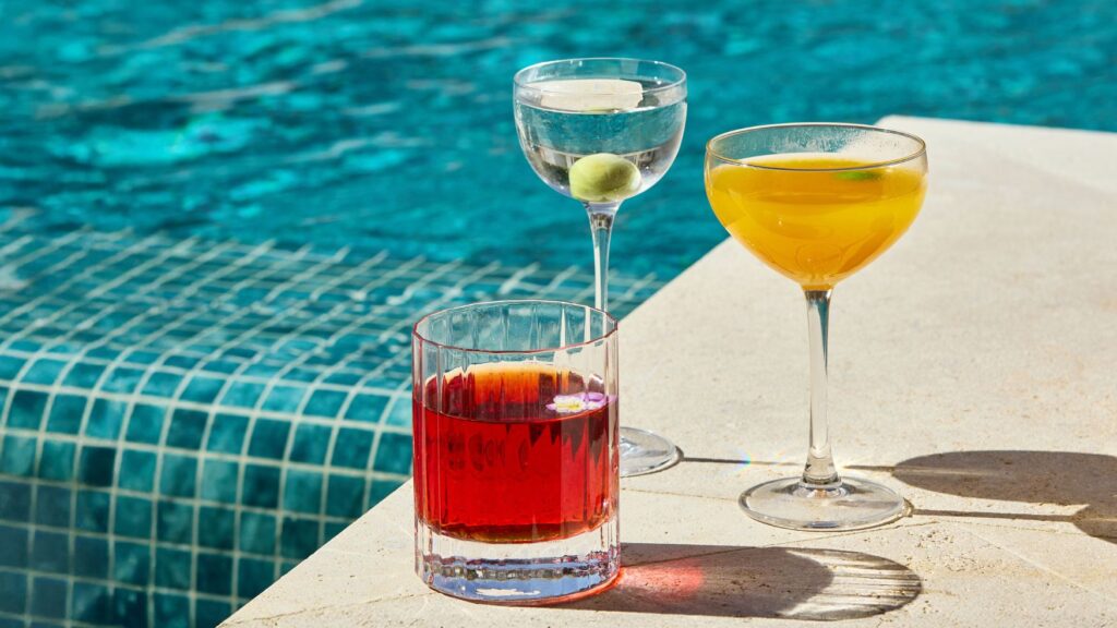 Three signature cocktails served poolside at Solaire Lounge, overlooking the resort swimming pool.
