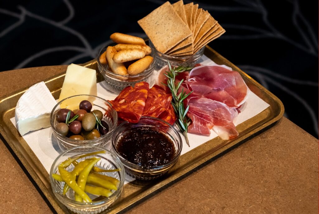Charcuterie board with cheese, prosciutto, salami, olives, crackers and dips on gold tray at Lotus Bar