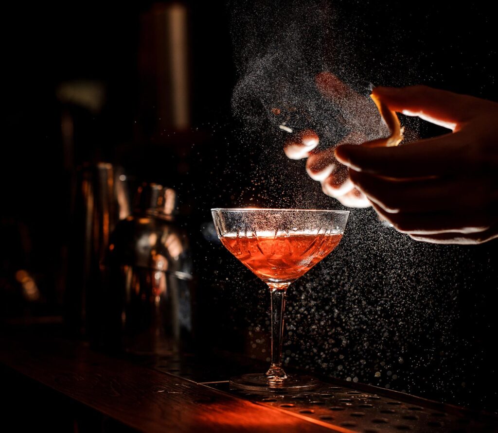 Bartender finishing a cocktail at Lotus Bar, with citrus garnish and misted aroma adding a refined, intimate bar experience
