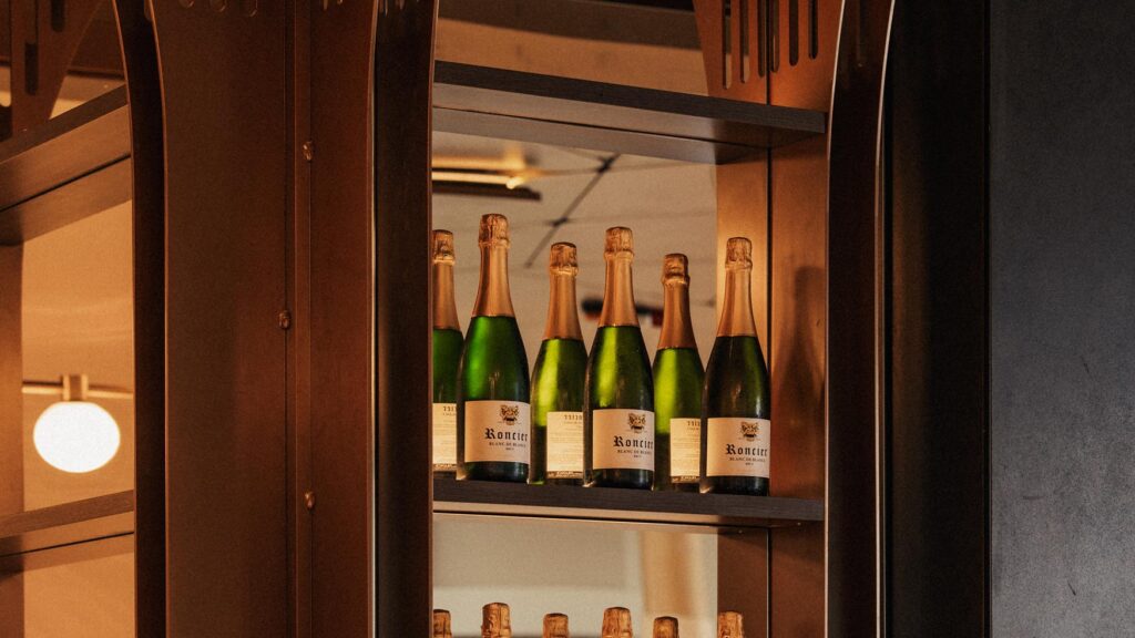 Champagne bottles lit up in a glass-front cabinet behind the bar at Lotus Bar