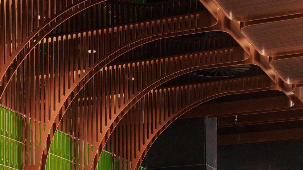 Curved copper ceiling panels and warm lighting details create an intimate, modern atmosphere inside Lotus Bar.