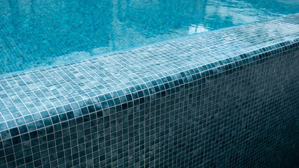 Close-up of a blue mosaic-tiled pool edge with rippling water at Solaire Lounge, a break between conference days