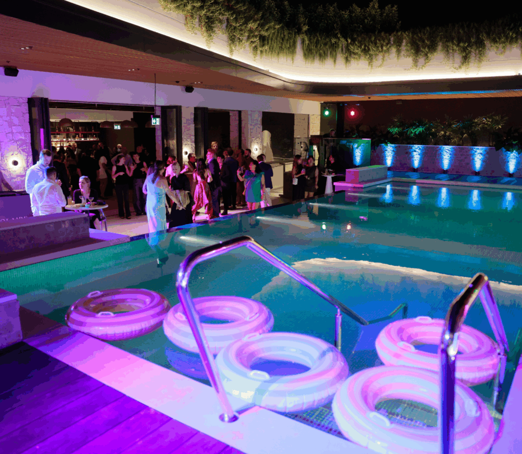 Illuminated swimming pool with floating rings and colourful lights, set for a stylish nighttime event at Solaire Lounge