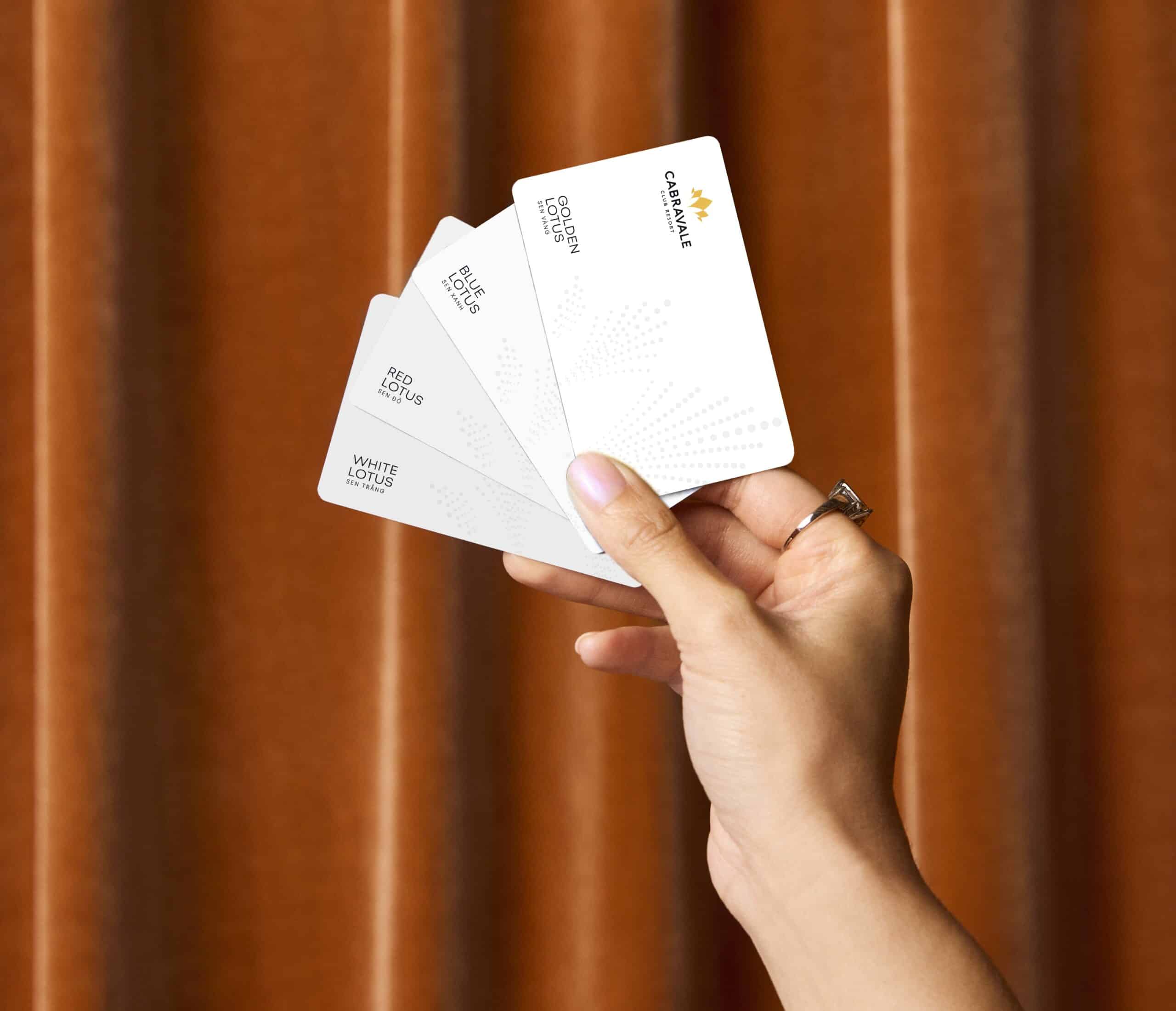 Hand holding Cabravale Group membership cards showing White Lotus, Red Lotus, Blue Lotus and Gold Lotus tiers