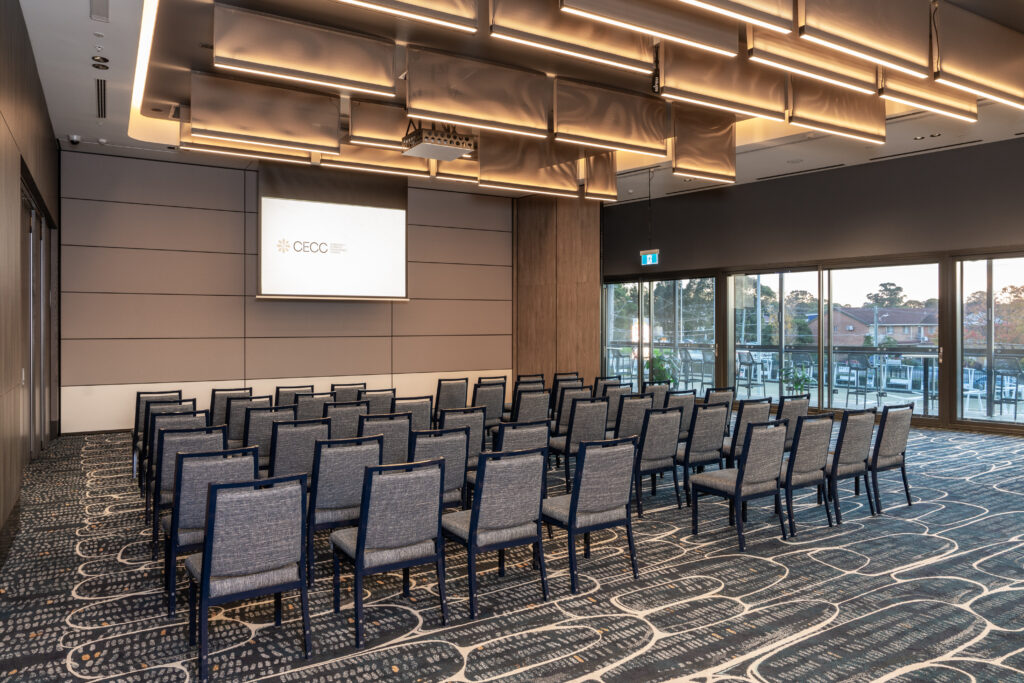 Theatre-style seating facing a presentation screen in a corporate event room at the Cabravale Events & Conference Centre