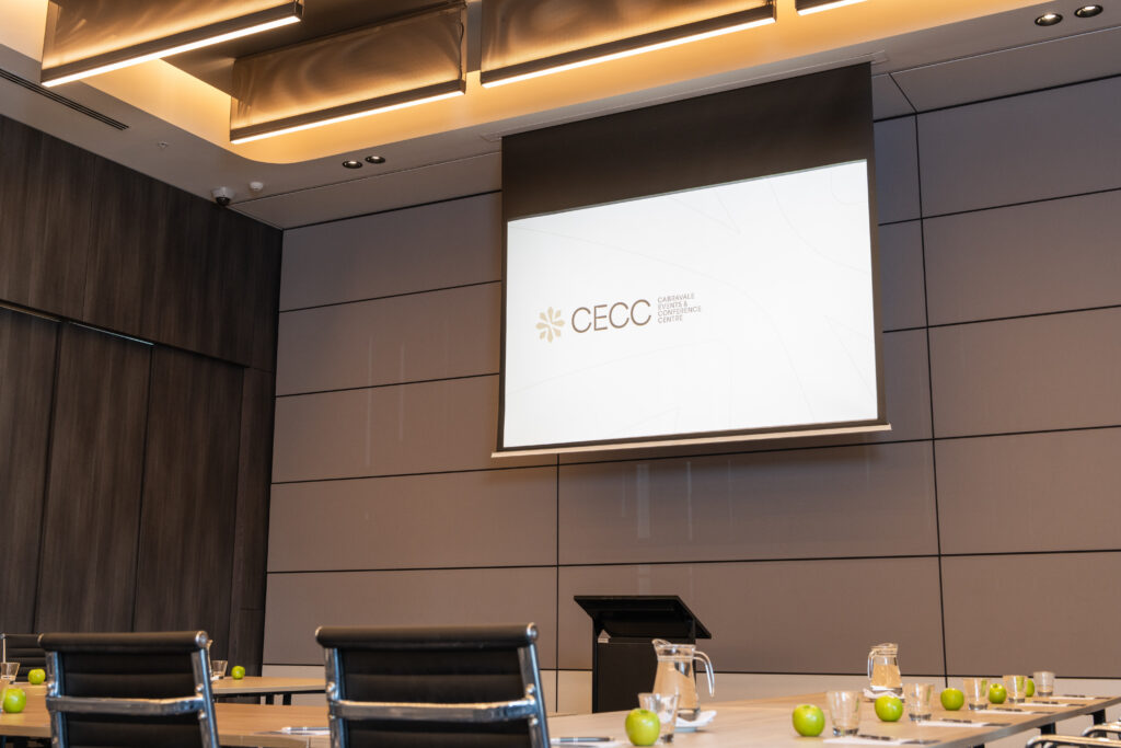 Conference room with a CECC presentation screen and tables set with water and green apples, ready for a 2026 conference