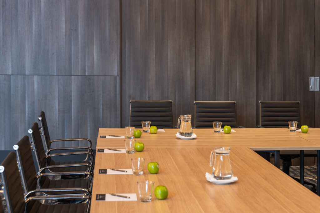 Boardroom tables set with water jugs, notepads and green apples, ready for planning a conference at Cabravale