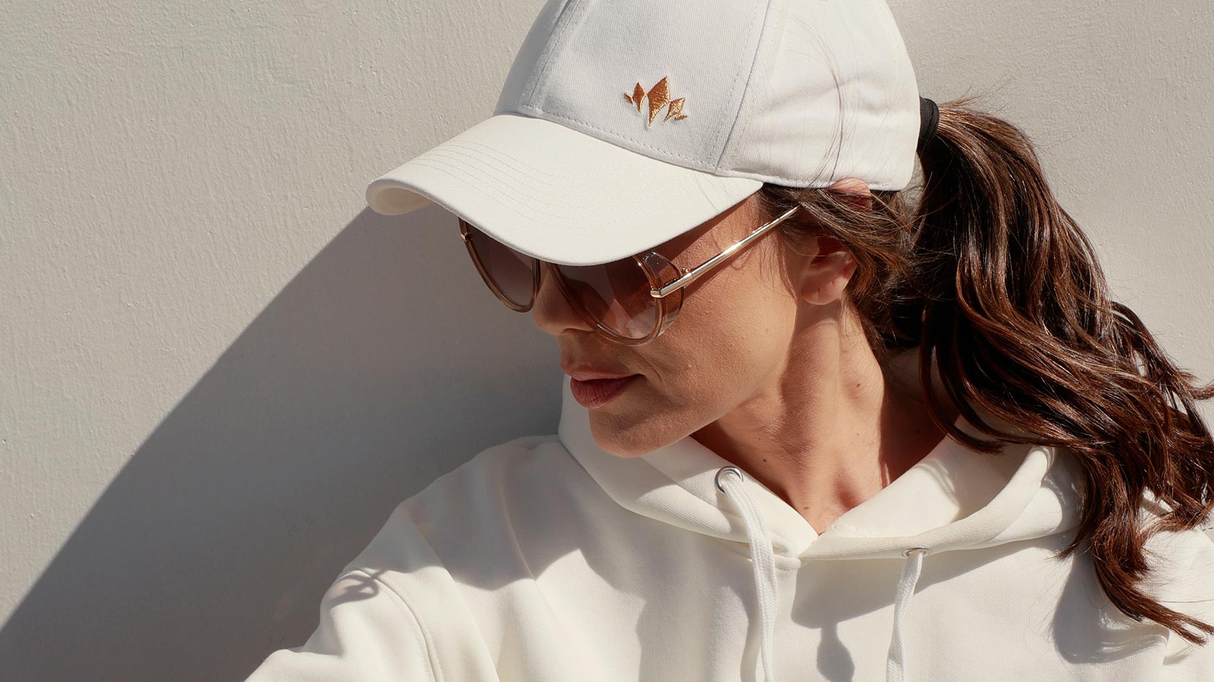 Woman wearing a white Cabravale Boutique cap and polo shirt, side profile