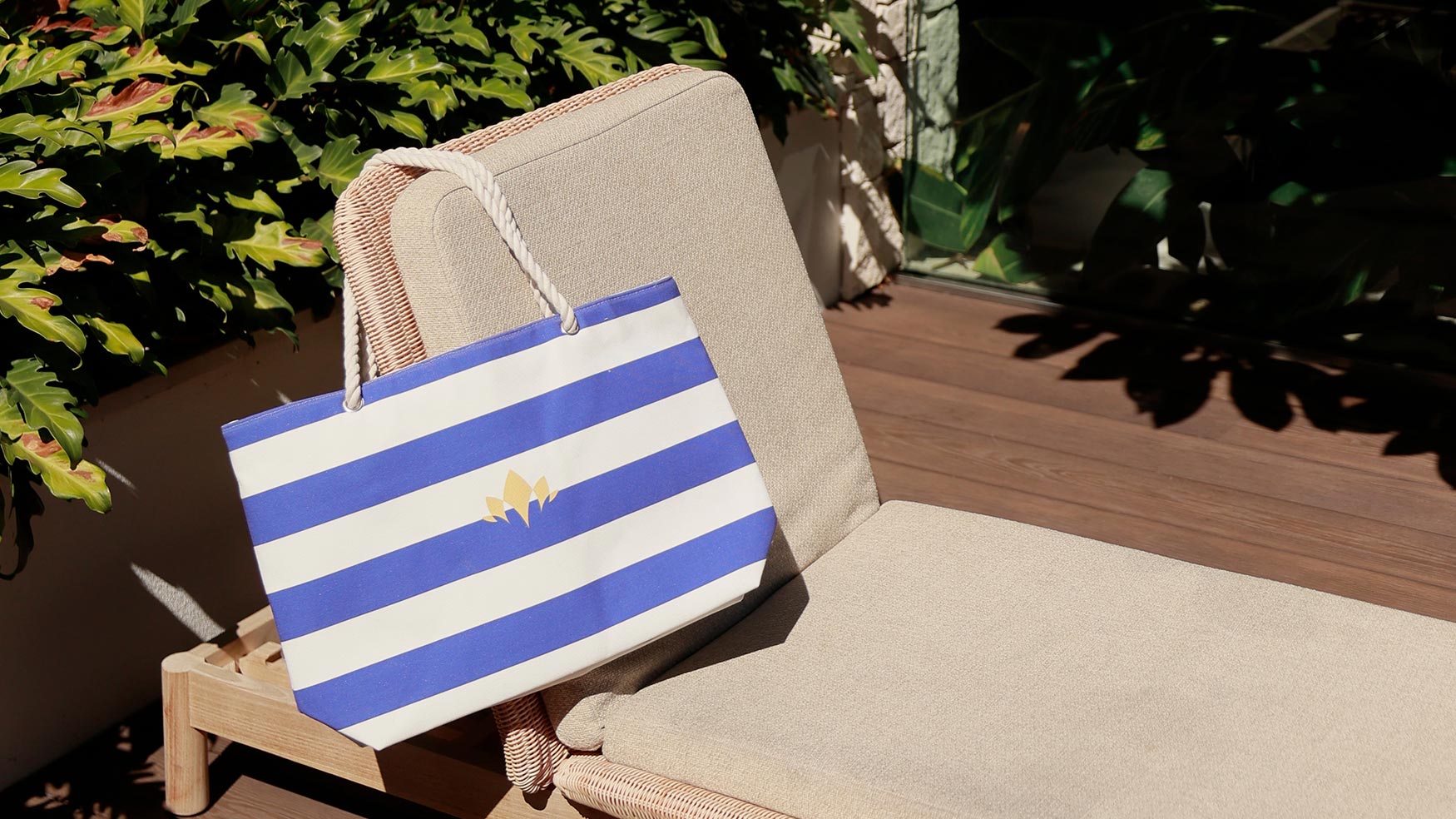 Blue and white striped Cabravale Boutique tote bag on a rattan chair outdoors
