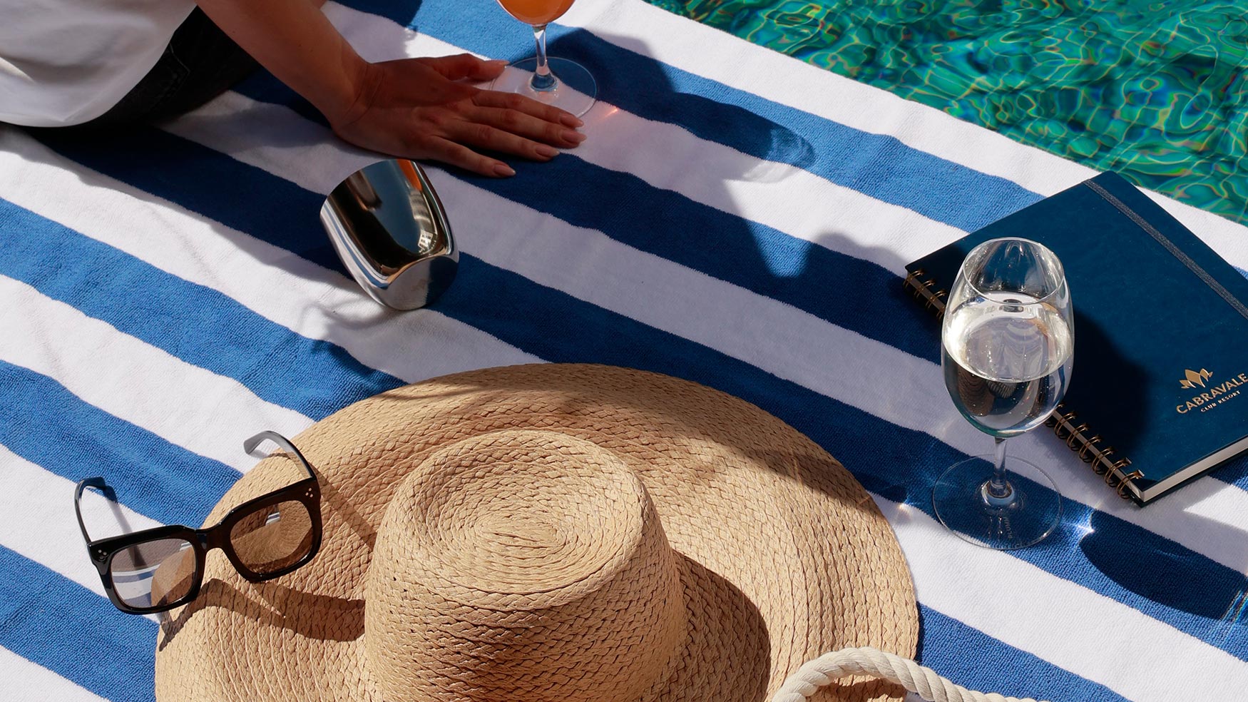 Cabravale Boutique sun hat, sunglasses and smart watch styled on a striped poolside towel