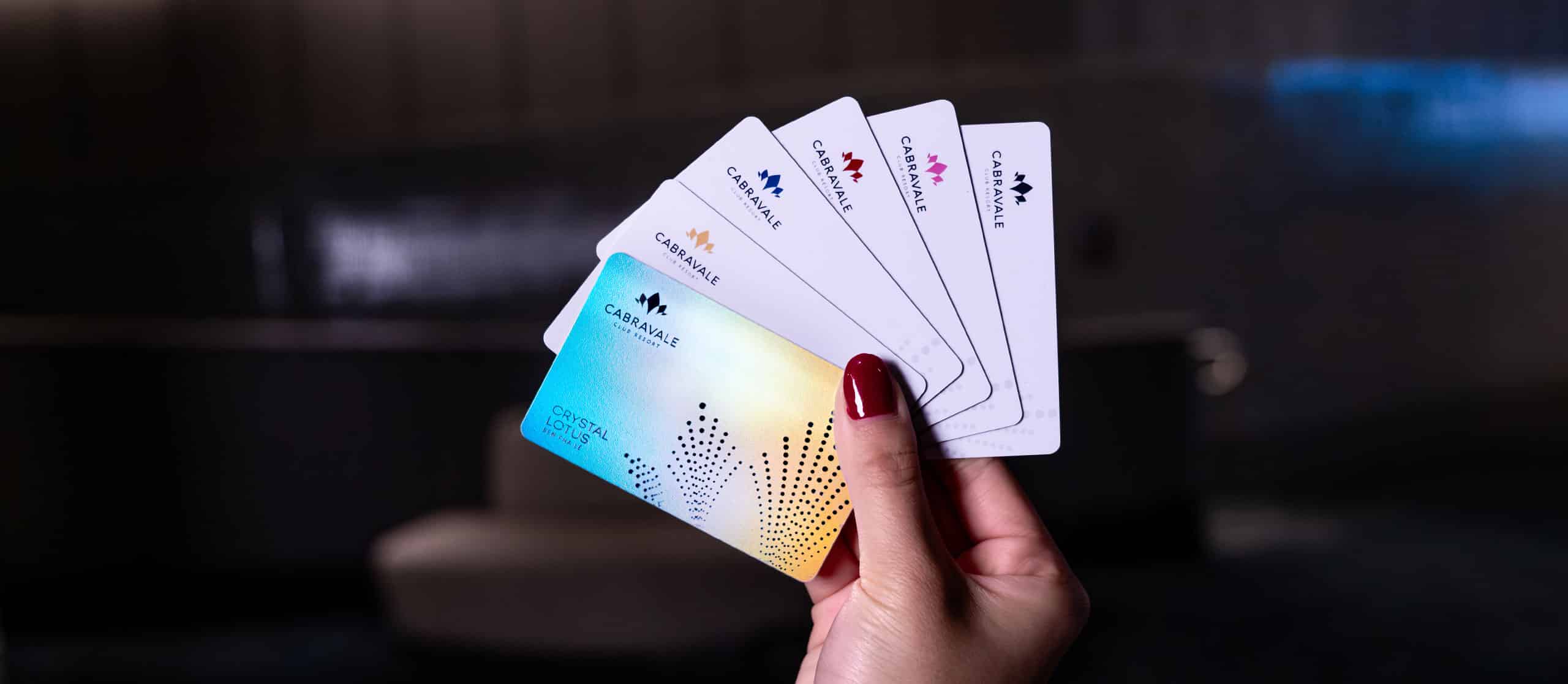 Hand holding Cabravale Group membership cards showing White Lotus, Pink Lotus, Red Lotus, Blue Lotus and Gold Lotus and Crystal Tiers
