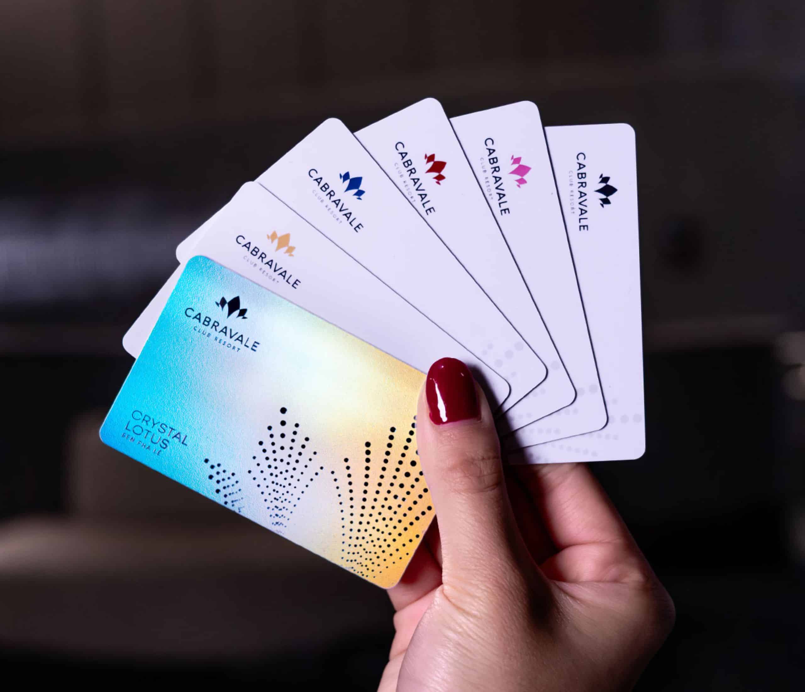 Hand holding Cabravale Group membership cards showing White Lotus, Pink Lotus, Red Lotus, Blue Lotus and Gold Lotus and Crystal Tiers
