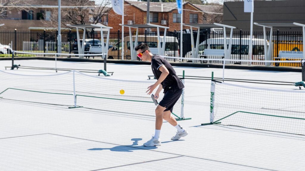 Player returning a shot on a sunny outdoor pickleball court in Cabramatta